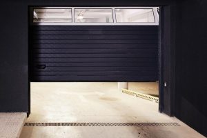 Black paneled garage door stopped partly open, with a window strip along the top