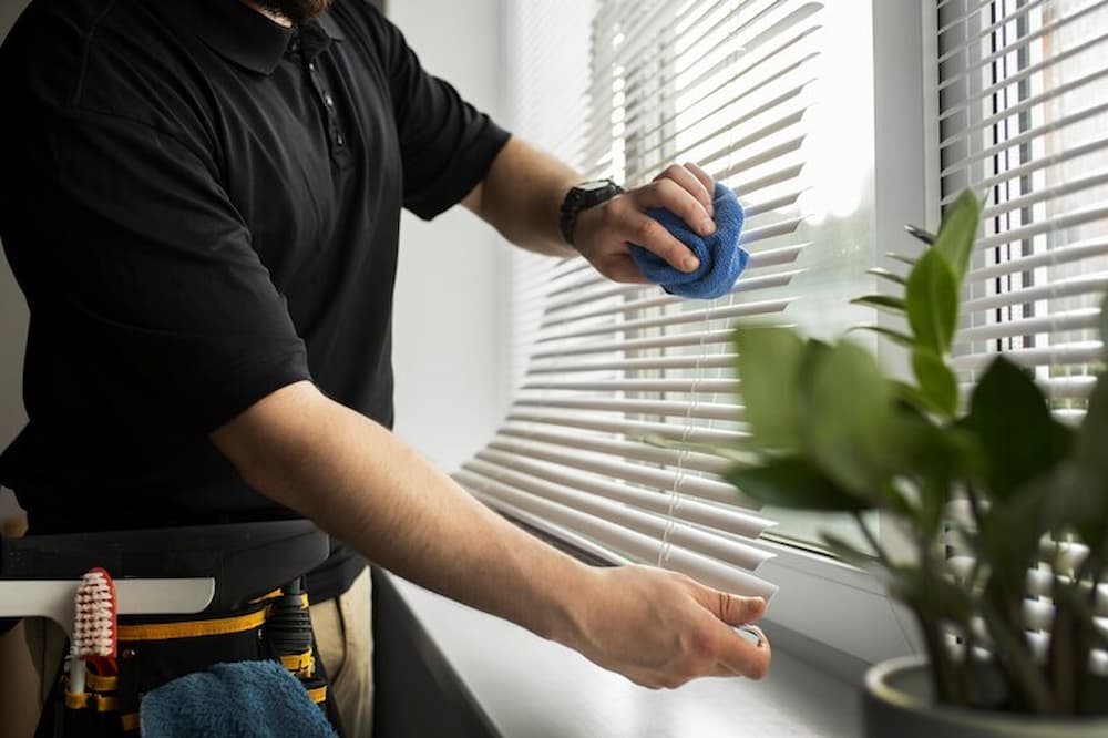 Hombre limpiando persianas con un paño